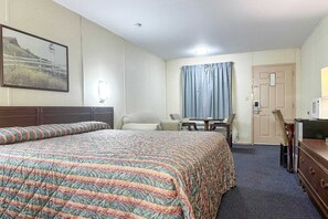 Ein Hotelzimmer mit einem großen Bett, einem Schreibtisch, einem Stuhl, einer Kommode und einer Tür.