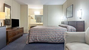 A hotel room with a bed, a dresser, a television, a mirror, and a framed picture on the wall. - Louisville, GA|King Bed|Smoking (Louisville, GA)