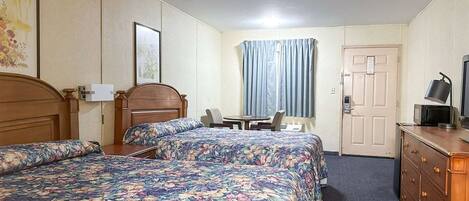 Ein Hotelzimmer mit zwei Betten, einem Schreibtisch, einem Stuhl, einem Schminktisch und einem Fernseher.