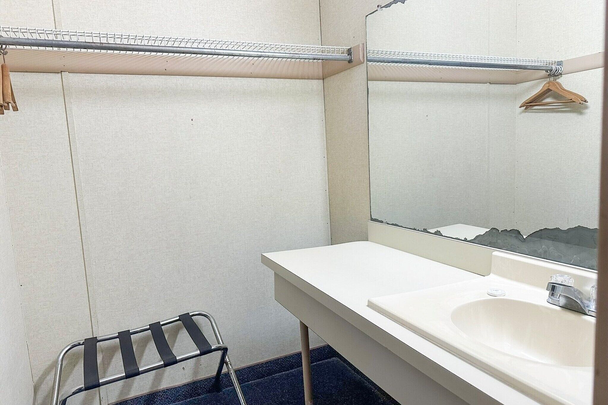 A bathroom with a white sink, mirror, and metal towel rack.