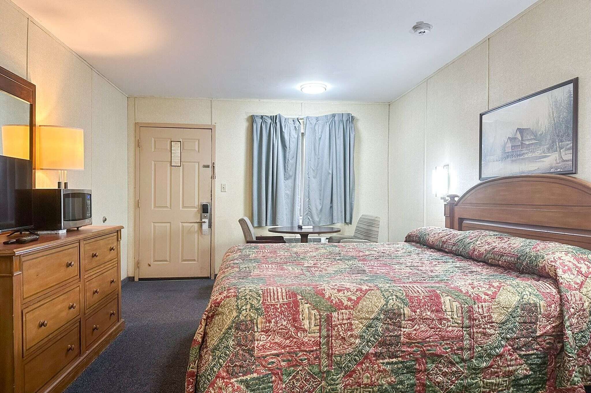 Una habitación de hotel con una cama, un escritorio, una silla, un televisor y un aparador.