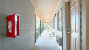 Un couloir avec un extincteur sur le côté gauche, une porte sur le côté droit et un banc au fond.