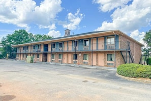 A motel with multiple rooms, a covered parking area, and a small hill with a gazebo.