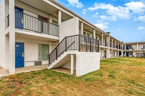 A multi-story motel with balconies, a central stairwell, and a grassy courtyard. - King Bed|Non-Smoking (Columbus OH)