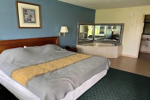 A hotel room with a bed, a bathroom with a mirror, a sink, and a framed picture on the wall.