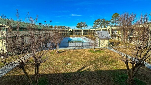 A courtyard with a swimming pool, surrounded by buildings with a simple architectural style. - King Bed with Kitchenette Non-Smoking (Milledgeville, GA)