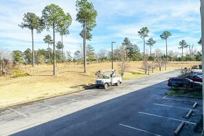 Um estacionamento com uma caminhonete branca, árvores e céu claro.