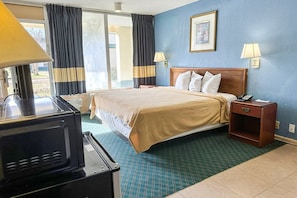 A hotel room with a bed, bedside lamps, a telephone, a nightstand, and a microwave. - Full Bed|Smoking|Milledgeville (Milledgeville, GA)