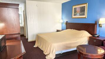 Habitación de hotel con cama, mesitas de noche, escritorio, silla, televisor y un cuadro en la pared.