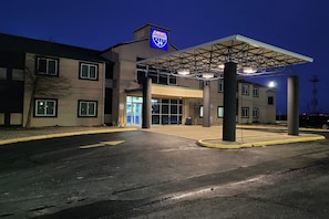 A modern building with a covered entrance, a sign for 'Modern St. 39,' and a parking lot.