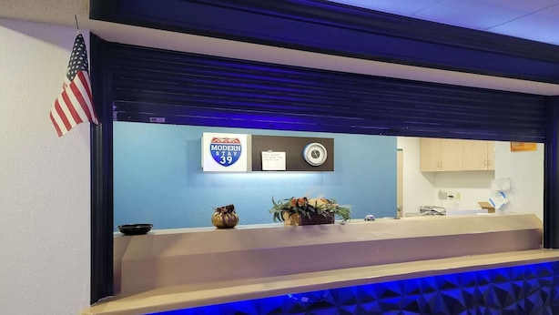 A reception desk with an American flag, a 'Modern Stay 39' sign, a clock, and a plant. - 2 Full Beds Non-Smoking (Minonk IL)