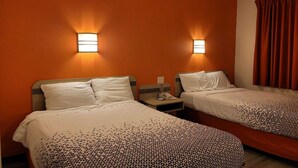 A hotel room with two beds, each with a pillow and a blanket, and two bedside tables with lamps. - 2 Full Beds Non-Smoking (Minonk IL)