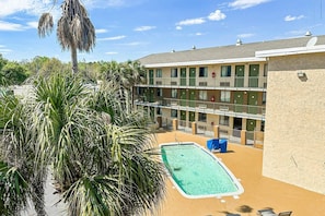 Ein Motel mit Schwimmbad, mehreren Balkonen und Palmen.