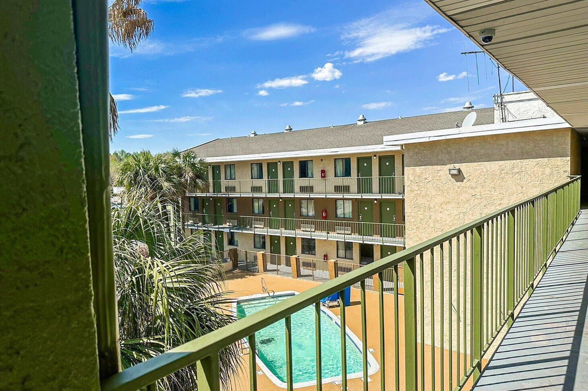 Ein mehrstöckiges Motel mit Pool, Balkonen und blauem Himmel.