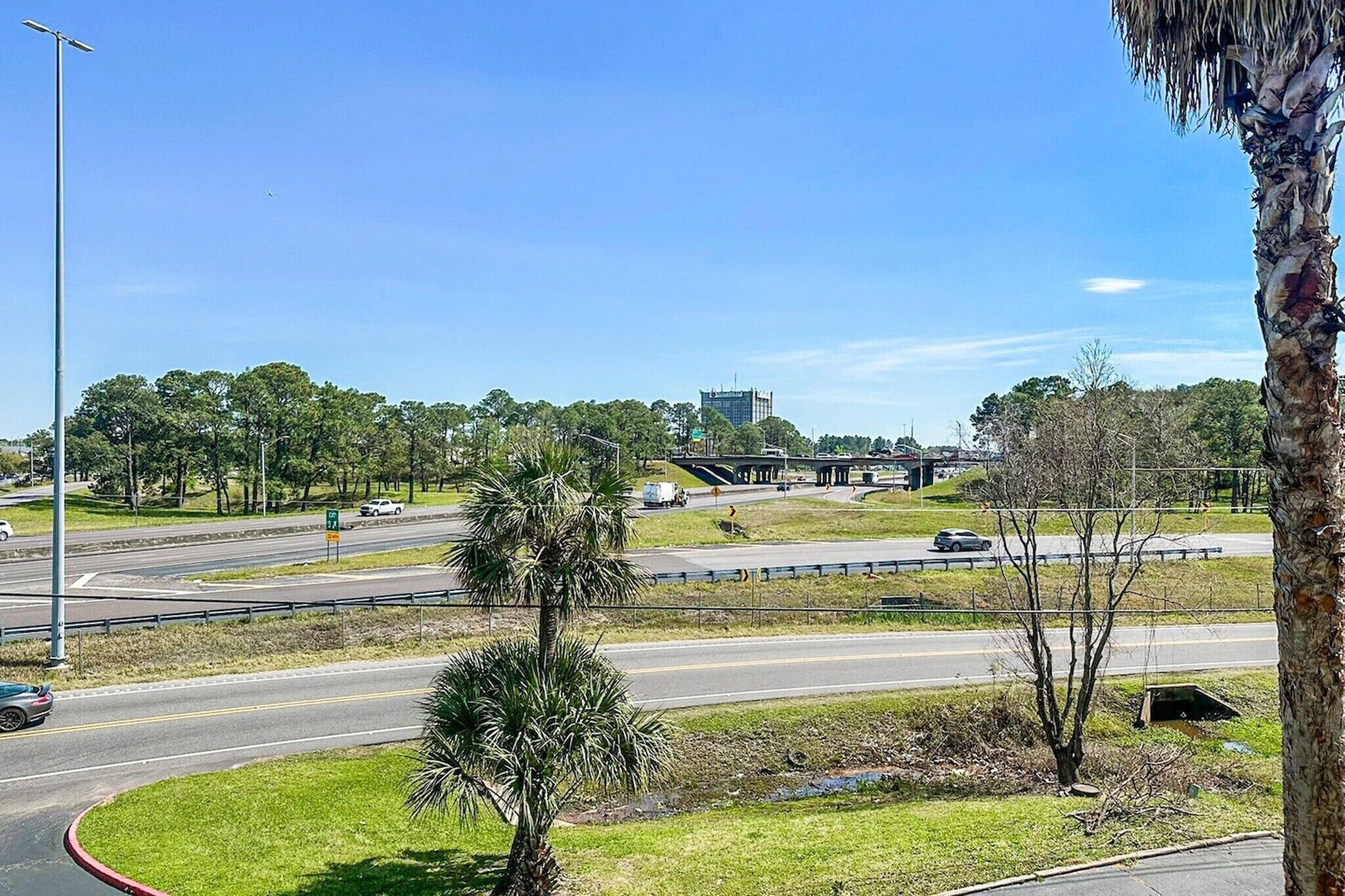 A highway interchange with multiple lanes, palm trees, and a clear blue sky.