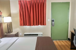 Ein Hotelzimmer mit einem Bett, einem Heizkörper, einer grünen Tür und einem roten Vorhang.