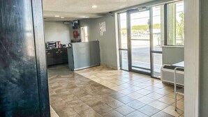 A clean, modern interior with a reception desk, a large window, and a visible air conditioning unit.