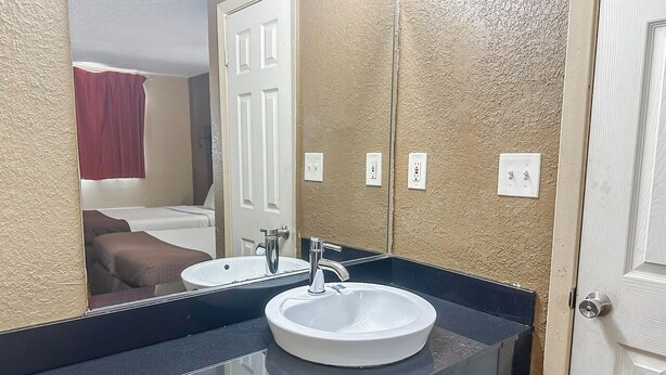A bathroom with a white sink, a mirror, and a door.