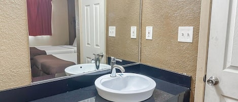 Une salle de bain avec un lavabo blanc, un miroir et une porte.
