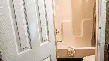 A bathroom with a bathtub, toilet, and a shower curtain.