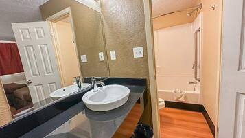 A bathroom with a double sink, a bathtub, and a shower.