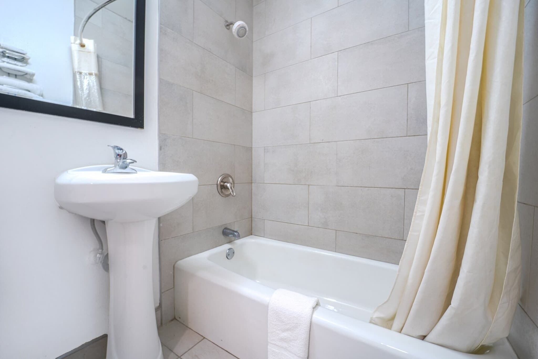 A bathroom with a white sink, a bathtub, and a shower curtain.
