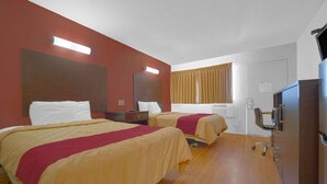 Een hotelkamer met twee bedden, een bureau, een stoel, een televisie en een raam met gordijnen.