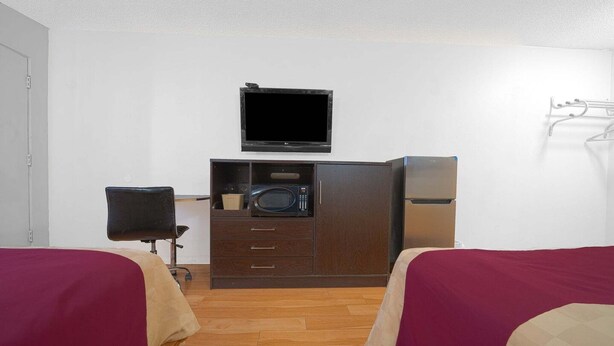 A room with two beds, a TV, a microwave, and a small cabinet. - 2 Full Beds|Non-Smoking (Mojave CA)
