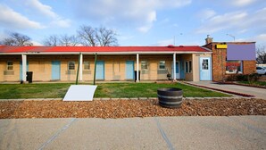 A motel with a red roof, a brick building, and a sign indicating it's open.