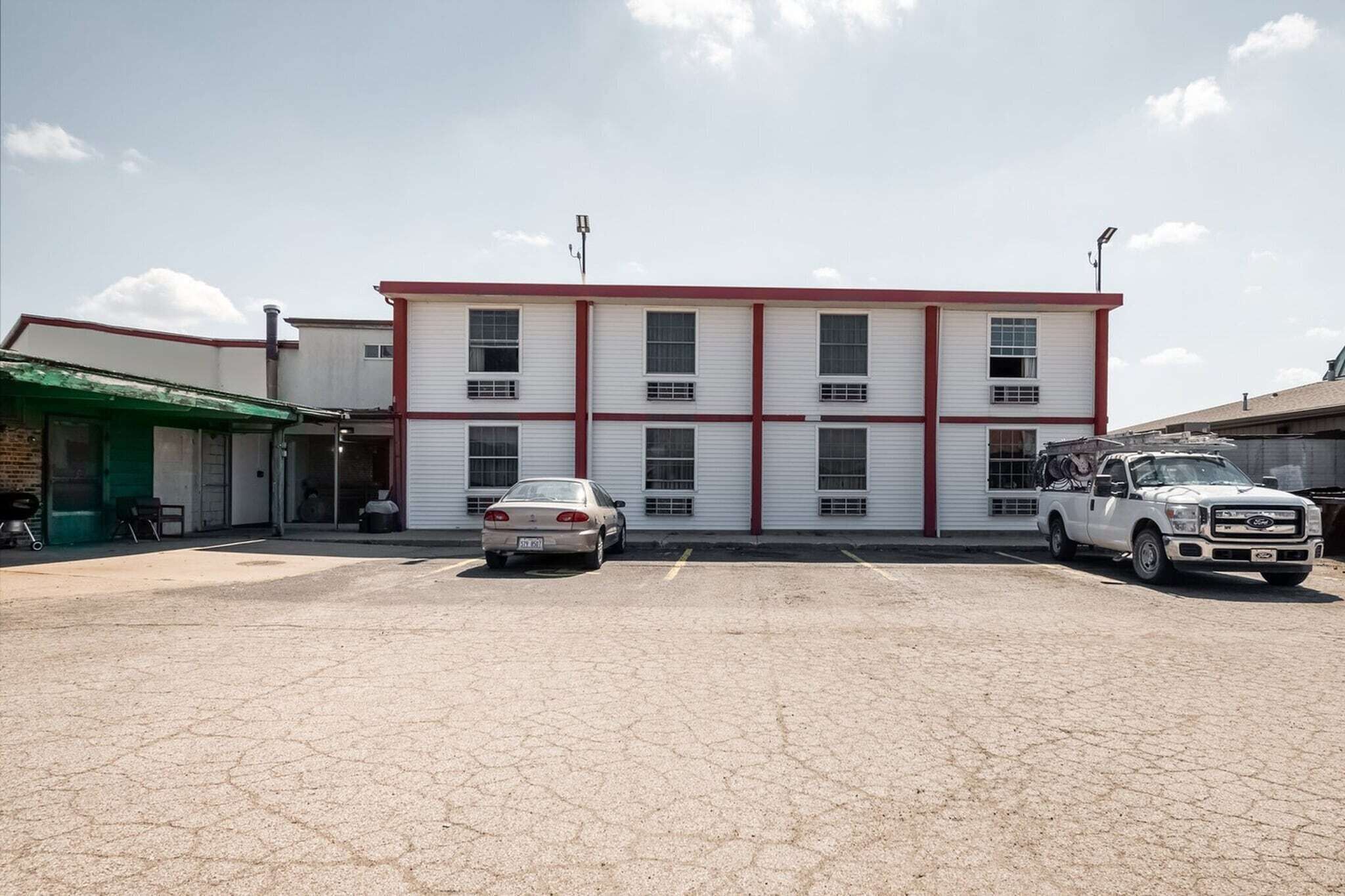 A building with a parking lot, a white car, and a white truck.