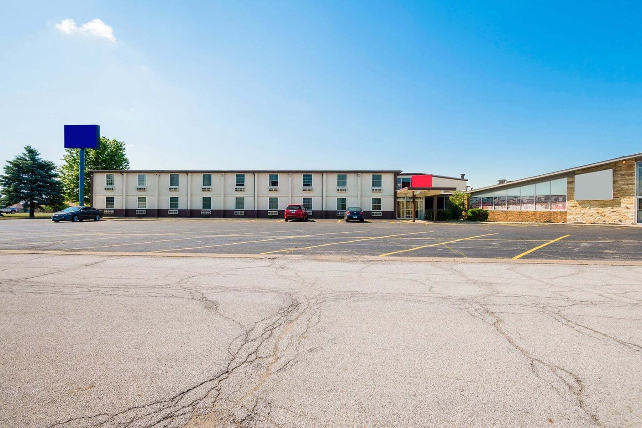 A parking lot with a building that has multiple windows and a flat roof.