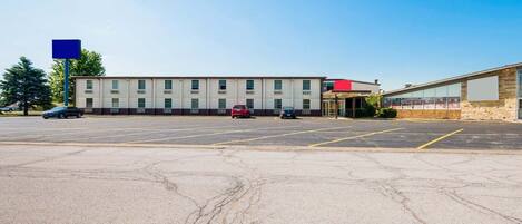 A parking lot with a building that has multiple windows and a flat roof.