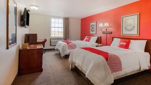 Une chambre d’hôtel avec deux lits, un bureau, une télévision et une fenêtre.
