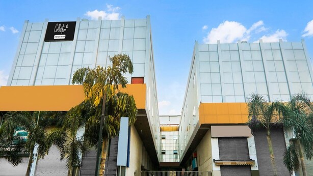 Um edifício moderno com fachada de vidro, uma placa com a palavra 'Collection' e uma entrada com portão.