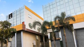 Um edifício moderno com grandes janelas, palmeiras e céu claro.