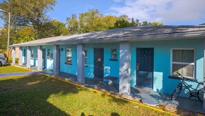 A single-story motel with a row of rooms, a covered parking area, and a bicycle parked outside. - Queen Bed|Kitchenette|Non-Smoking (Merritt Island FL)