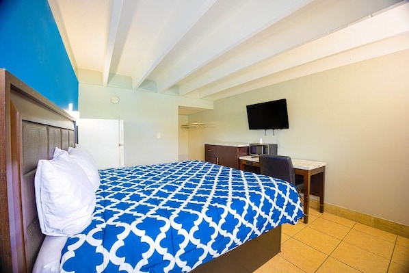A hotel room with a bed, a desk, a chair, a television, and a bathroom.