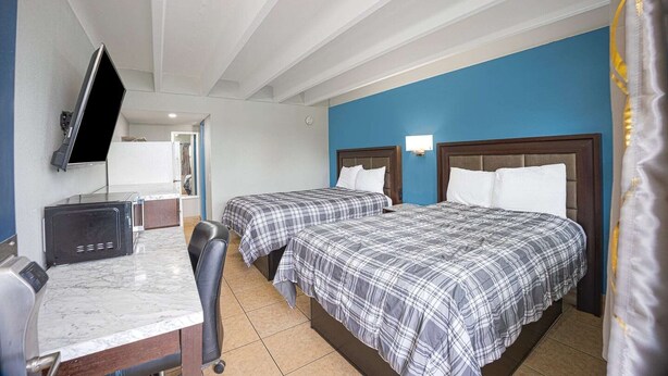 A hotel room with two beds, a TV, a desk, and a chair. - 2 Full Beds|Non-Smoking (Merritt Island FL)
