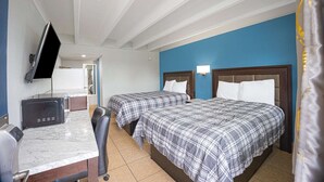 Ein Hotelzimmer mit zwei Betten, einem Fernseher, einem Schreibtisch und einem Sessel.