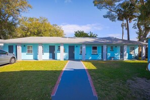 A single-story motel with a blue exterior, a central entrance, and a car parked in the driveway. - 2 Full Beds|Non-Smoking (Merritt Island FL)