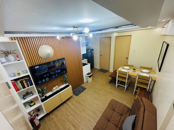 Una sala de estar moderna con televisor, pared de paneles de madera, comedor y sofá.