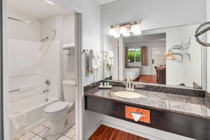 A bathroom with a bathtub, toilet, sink, and a large mirror.