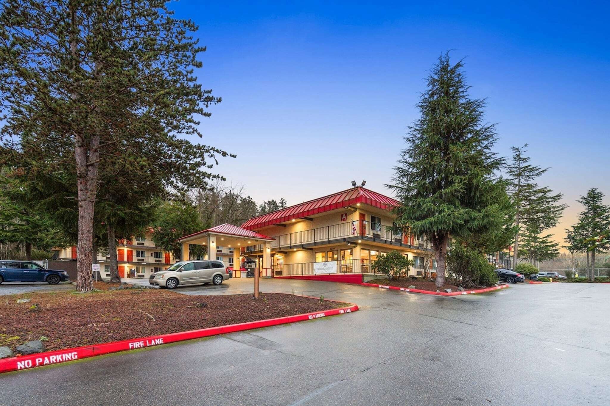 A building with a red roof, multiple floors, and a fire lane in front.