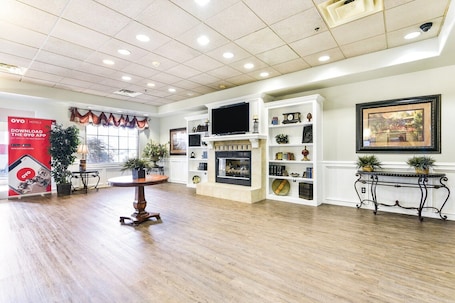A spacious hotel lobby with a fireplace, television, and shelves with decorative items.