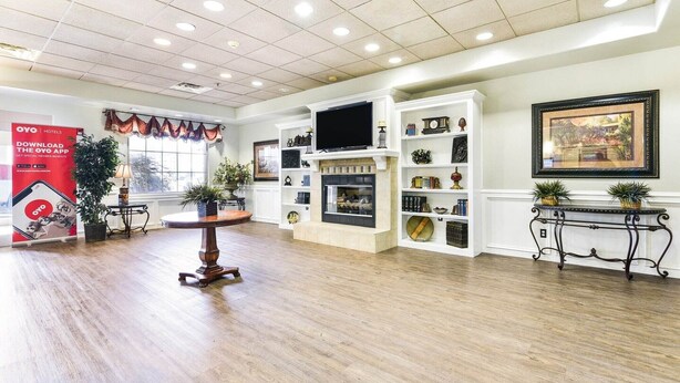 Een ruime hotel lobby met een open haard, televisie en diverse decoratieve objecten.