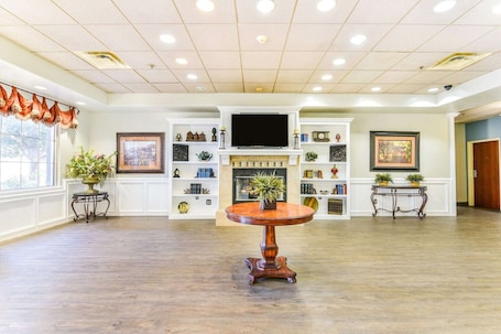 A spacious room with a fireplace, a television, and a round table with a vase.