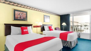 Habitación de hotel con dos camas, un ventanal grande y un balcón.