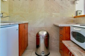 Une cuisine compacte équipée d’une poubelle, d’un four à micro-ondes et d’un petit plan de travail.