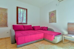 Ein Zimmer mit Ecksofa, einem kleinen Tisch und Bildern an den Wänden.
