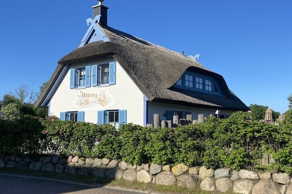Ein traditionelles Gebäude mit einem Strohdach und einem Schild, auf dem 'Haus Viking' steht.